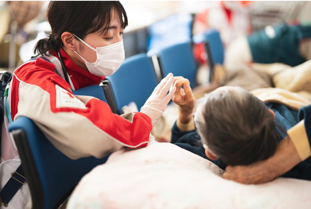 上写真は、日本赤十字社HPより石川県七尾市の避難所で巡回診療を行う福岡県支部救護班（福岡赤十字病院）。令和6年能登半島地震の被災状況は、揺れの被害、津波被害、延焼火災、土砂崩れ、液状化、孤立地区、低体温症、災害関連死、避難所環境、広域避難対策などなど、厳寒下での大震災の様相を呈している。この地の人びとの不安と今後の見通しがつかない状況は、災害列島で生活する私たちのだれもが共有し得るものではないか
